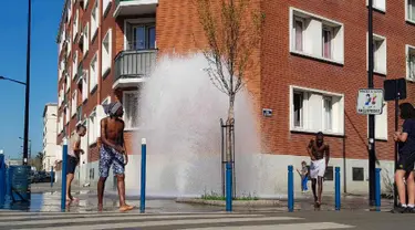 Sejumlah pemuda mendinginkan tubuh di air hidran yang terbuka selama cuaca panas di Aubervilliers, sebelah utara Paris, (19/4). (AFP Photo/Amine Guedaim)