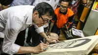 Menteri Hukum dan HAM, Yasonna Laoly menandatangani lukisan dirinya saat mengunjungi LP Salemba, Jakarta, Rabu (9/3/2016). Kunjungan Menkumham tersebut untuk mengontrol peredaran narkotika di dalam Lapas. (Liputan6.com/Yoppy Renato)