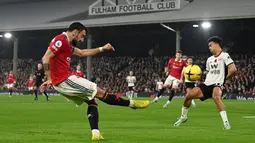 Gelandang Manchester United (MU) Bruno Fernandes  mengumpan bola ketika bek Fulham Antonee Robinson mencoba untuk memblokir pada pekan ke-16 Liga Inggris 2022/2023 di Craven Cottage, London, Minggu (13/11/2022). Kemenangan ini menjaga jarak Man United dengan empat besar. (Photo by Glyn KIRK / AFP)