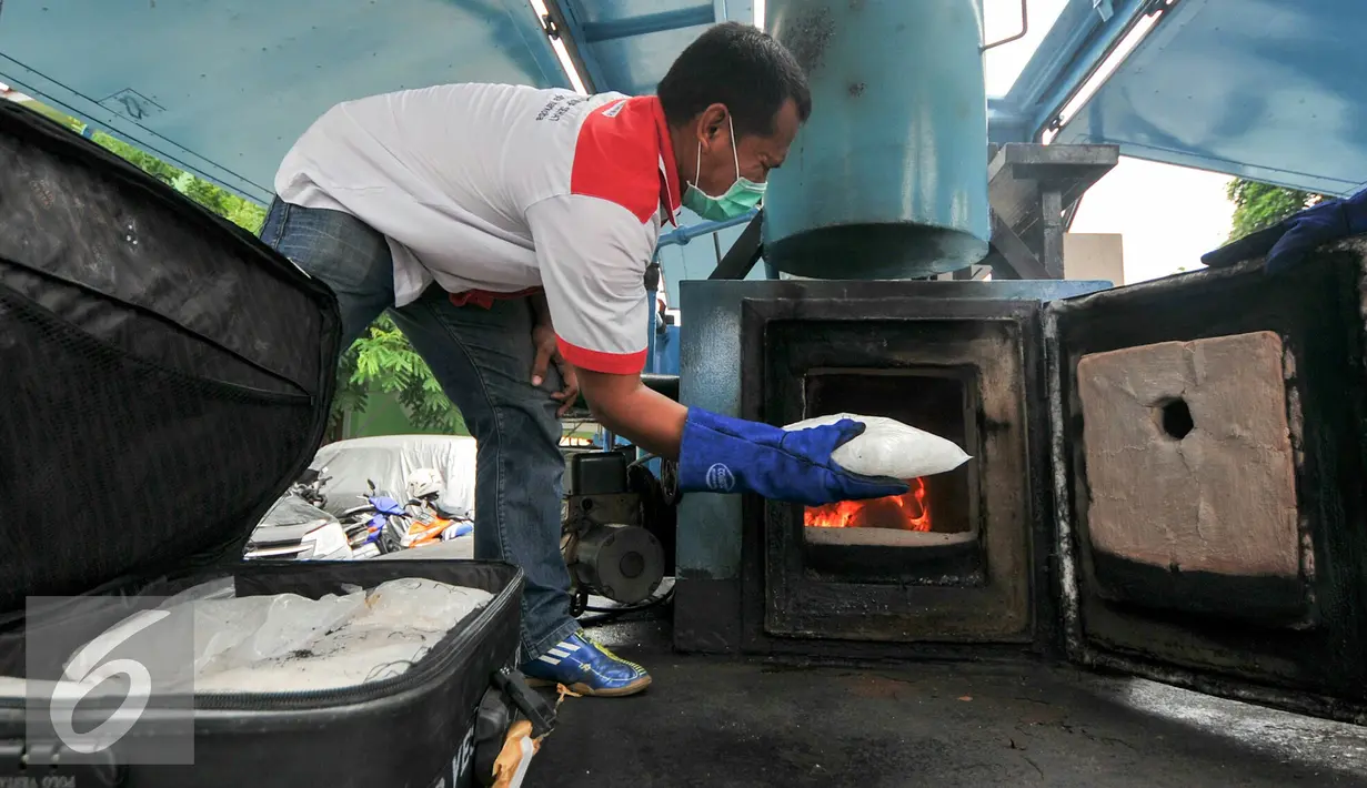 Petugas BNN memasukan barang bukti sabu ke dalam tunggu pembakaran untuk dimusnahkan, Jakarta, Selasa (15/12). BNN musnahkan 164 kg sabu dari hasil pengungkapan 5 kasus berbeda. (Liputan6.com/Yoppy Renato)