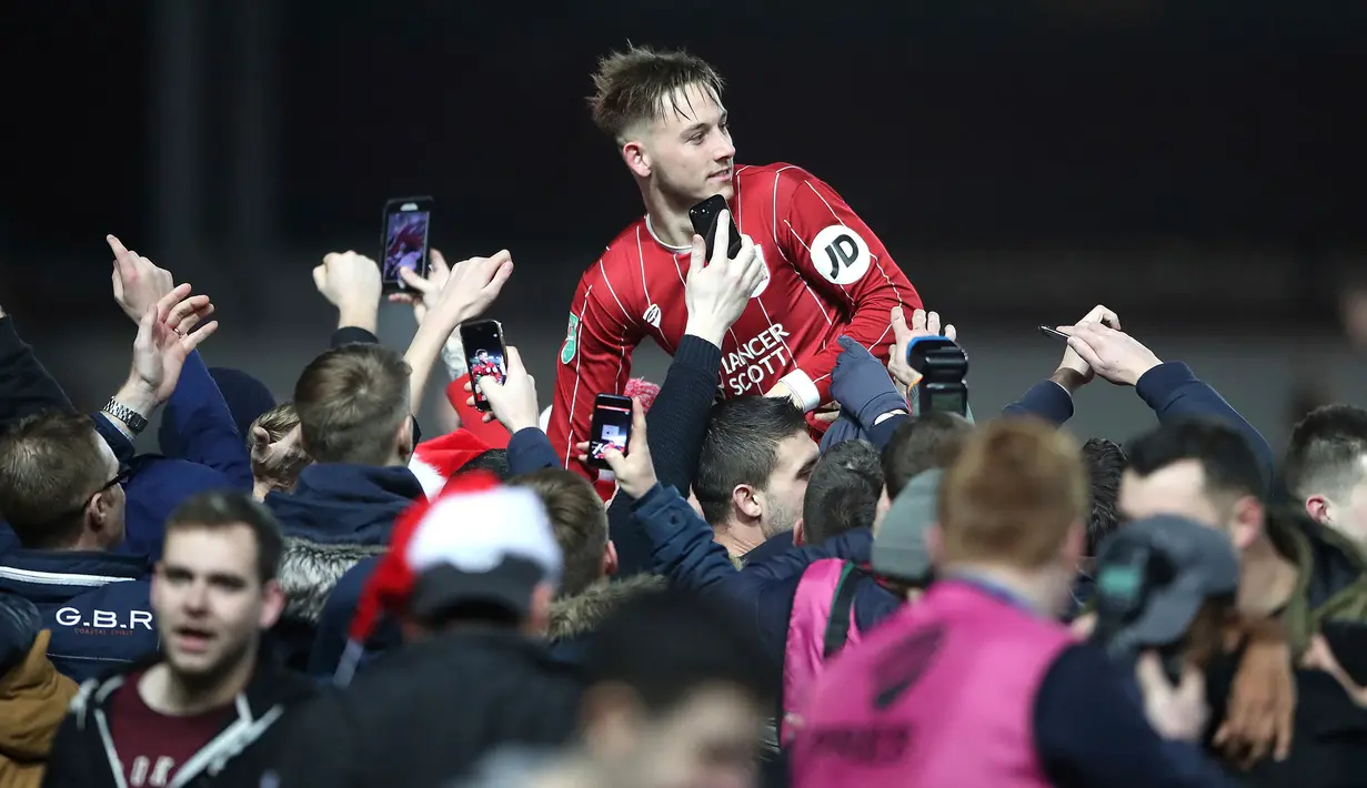 Para fans mengangkat pemain Bristol City, Josh Brownhill ke udara setelah menang atas Manchester United pada perempat final Piala Liga Inggris di Ashton Gate, Kamis (21/12). Klub kasta kedua Bristol City sukses menyingkirkan MU 2-1. (Nick Potts/PA via AP)