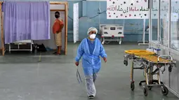 Seorang dokter Tunisia merawat seorang pasien di gym yang diubah untuk menangani lonjakan infeksi COVID-19 di pusat kota Kairouan pada 4 Juli 2021. Tunisia tengah berjuang menghadapi tsunami COVID-19 sementara jumlah orang yang meninggal akibat virus corona terus melonjak tinggi. (FETHI BELAID/AFP)