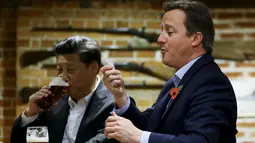 PM Inggris David Cameron (kanan) memegang beberapa lembar untuk membayar minuman yang ia pesan di sebuah bar, Princess Risborough, Inggris, Kamis (22/10/2015). Kedua pemimpin ini terlihat akrab saat minum bis bersama. (REUTERS/Kirsty Wigglesworth)