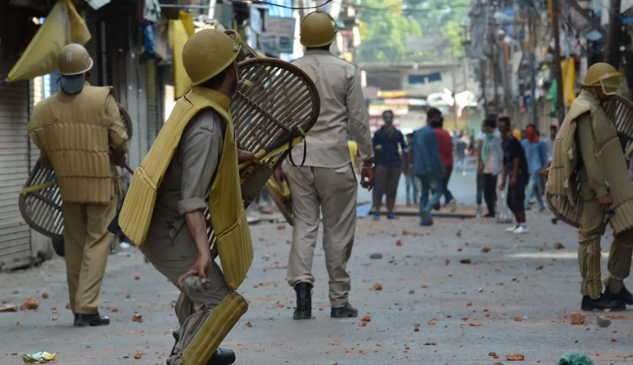 Polisi India melemparkan batu ke arah demonstran saat bentrok dengan warga Kashmir di Srinagar, India (11/7). Menurut kepolisian sebanyak 30 orang meninggal dalam bentrokan yang berlangsung selama tiga hari tersebut. (AFP PHOTO/Tauseef MUSTAFA)