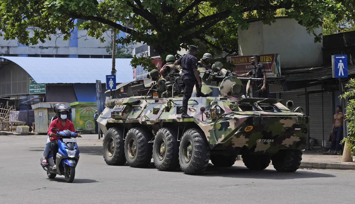 <p>Pengendara motor melewati tentara Sri Lanka yang berpatroli selama jam malam di Kolombo, Rabu, 11 Mei 2022. Kementerian pertahanan Sri Lanka pada Selasa memerintahkan pasukan keamanan untuk menembak siapa pun yang menyebabkan korban jiwa atau properti publik untuk mencegah pembakaran yang meluas dan kekerasan massa yang menargetkan pendukung pemerintah. (AP Photo/Eranga Jayawardena)</p>