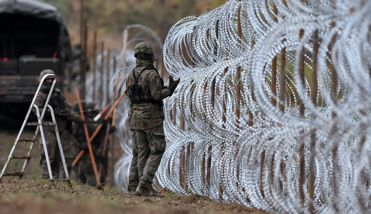 Tentara Polandia mulai memasang penghalang kawat berduri di sepanjang perbatasan Polandia dengan eksklave Rusia, Kaliningrad di Wisztyniec, Polandia, Rabu (2/11/2022). Perbatasan itu menjadi pusat krisis migrasi besar karena sejumlah besar orang Asia dan Afrika menyeberang secara ilegal di sana. (AP Photo/Michal Kosc)