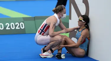Atlet Belgia Claire Michel dibantu oleh atlet Norwegia Lotte Miller setelah menyelesaikan kompetisi triathlon individu putri Olimpiade Tokyo 2020 di Tokyo, Jepang, 27 Juli 2021. (AP Photo/David Goldman)