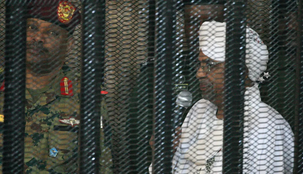 Presiden terguling Sudan, Omar al-Bashir ditempatkan di kandang terdakwa selama menjalani persidangan atas dakwaan korupsi di pengadilan di Khartoum, Senin (19/8/2019). Bashir  didakwa dengan tuduhan korupsi, kepemilikan mata uang asing dan menerima gratifikasi. (Ebrahim HAMID / AFP)