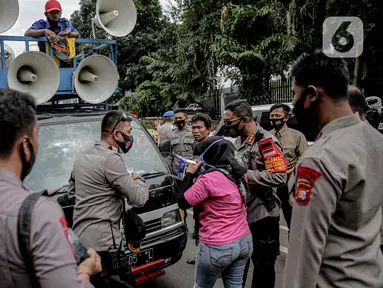 Petugas kepolisian beradu argumen saat memberhentikan mobil komando aksi di sekitar Gedung DPR, Jakarta, Jumat (14/8/2020). Polda Metro Jaya melarang adanya unjuk rasa di depan Gedung DPR/MPR yang bertepatan dengan sidang tahunan. (Liputan6.com/Faizal Fanani)
