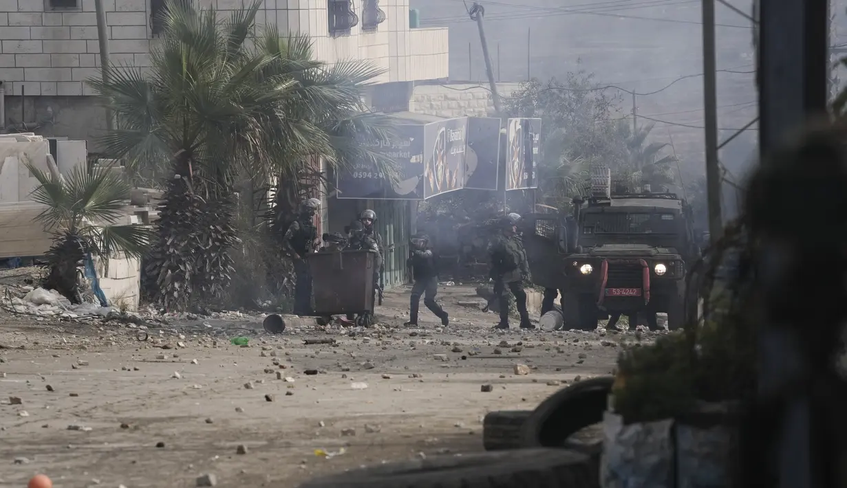 Pasukan keamanan Israel mengambil posisi selama bentrokan dengan pengunjuk rasa Palestina setelah pemakaman Mufid Khalil di desa Beit Ummar, Tepi Barat, dekat Hebron (29/11/2022). Militer Israel mengatakan tentara menembaki warga Palestina yang melemparkan batu dan alat peledak improvisasi dan menembak pasukan. (AP Photo/Mahmoud Illean)