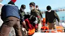 Petugas penyelamat saat menggotong mayat imigran di distrik Altinoluk, Balikesir, Turki, (8/2). Mayat imigran ini ditemukan sedang tenggelam saat mencoba menyeberang dari Turki ke Yunani. (STR / AFP)