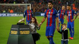 Striker Barcelona, Luis Suarez, didampingi anaknya saat menunjukan Sepatu Emas jelang laga La Liga melawan Granada di Stadion Nou Camp, Spanyol, Sabtu (29/10/2016). Suarez meraih gelar ini usai mencetak 40 gol pada musim lalu. (AFP/Lluis Gene)