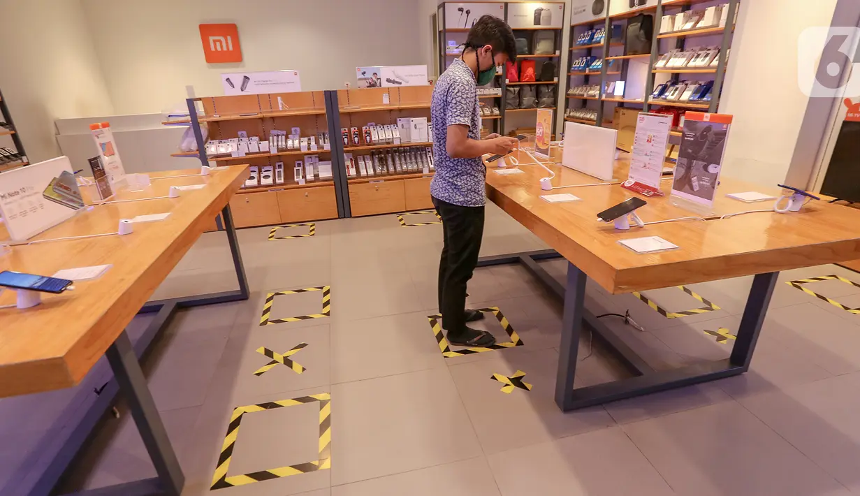 Karyawan tenant handphone berdiri diatas tanda physical distancing di Lippo Mall Puri, Jakarta, Rabu (3/6/2020). Lippo Malls Indonesia (LMI) menerapkan prosedur kebersihan dan keamanan bagi pengunjung agar masyarakat tetap produktif, disiplin dan waspada terhadap penyebaran Covid-19. (Liputan6.com/F
