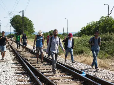 Sejumlah imigran berjalan menyusuri rel kereta api saat perjalanan menuju Gevgelija, wilayah perbatasan Macedonia-Yunani, Kamis (9/7/2015). Mereka menempuh ribuan kilometer agar dapat mengejar kereta api tujuan Serbia. (AFP PHOTO/Robert ATANASOVSKI)