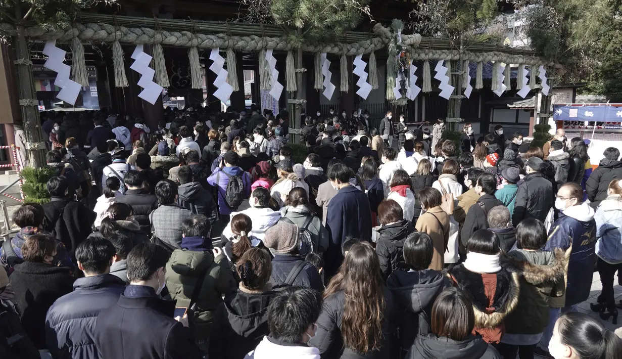 Pengunjung mengantre untuk berdoa memohon keberuntungan selama "hatsumode", atau kunjungan pertama mereka tahun ini ke kuil atau kuil, di kuil Buddha Kawasaki Daishi di Kawasaki, dekat Tokyo, Senin (3/1/2022). (AP Photo/Eugene Hoshiko)