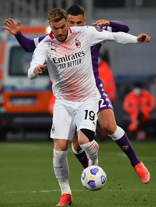 Bek AC Milan, Theo Hernandez membawa bola dari kejaran gelandang Fiorentina, Valentin Eysseric pada pertandingan Liga Serie A Italia di stadion Artemio Franchi, Italia (22/3/2021). Hasil ini membuat AC Milan memangkas jarak poin dengan Inter Milan di puncak klasemen. (AFP/Tiziana Fabi)