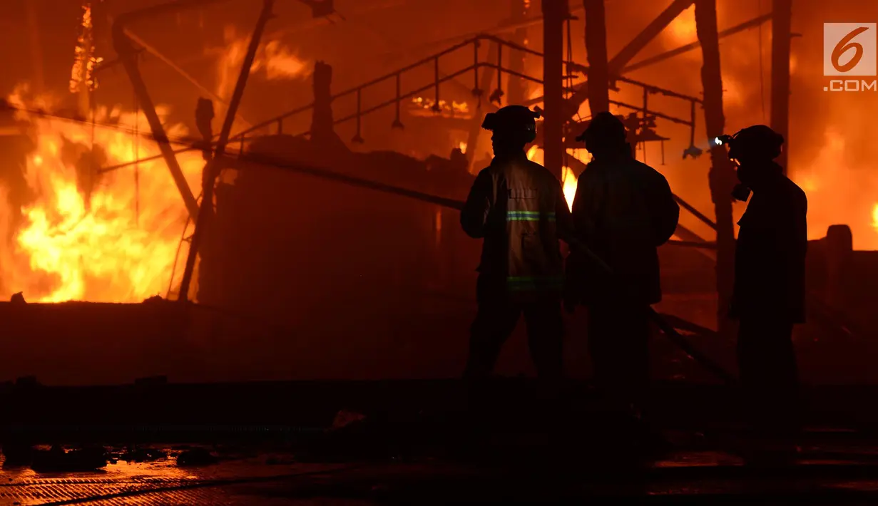 Petugas damkar berusaha menjinakan api yang membakar kapal nelayan di Pelabuhan Muara Baru, Penjaringan, Jakarta Utara, Sabtu (23/2). Sebanyak 18 kapal nelayan terbakar yang belum diketahui penyebabnya. (merdeka.com/Imam Bukhori)