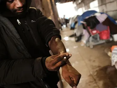 Seorang pria menggunakan heroin di bawah jembatan yang menjadi pusat penggunaan heroin di Kensington, Philadelphia (24/1). Menurut DAE Amerika Serikat, penggunaan heroin telah berlipat ganda di seluruh negeri sejak 2010. (Spencer Platt/Getty Images/AFP)
