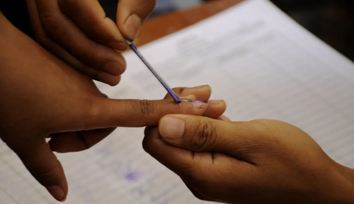 Sebelum menggunakan hak politiknya, jari para pemilih di India diberikan tanda tinta oleh petugas pemilihan setempat. (AFP PHOTO/Arindam DEY)