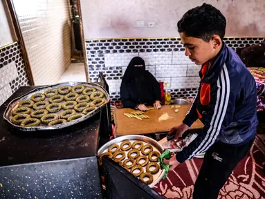 Anggota keluarga Palestina menyiapkan kue-kue tradisional untuk dijual sebagai persiapan liburan Idul Fitri mendatang, di kota Rafah, Jalur Gaza, Selasa (4/5/2021). Pembuatan kue tradisional untuk Hari Raya Idul Fitri atau Lebaran yang akan datang menandai akhir bulan Ramadhan. (KATA KHATIB/AFP)