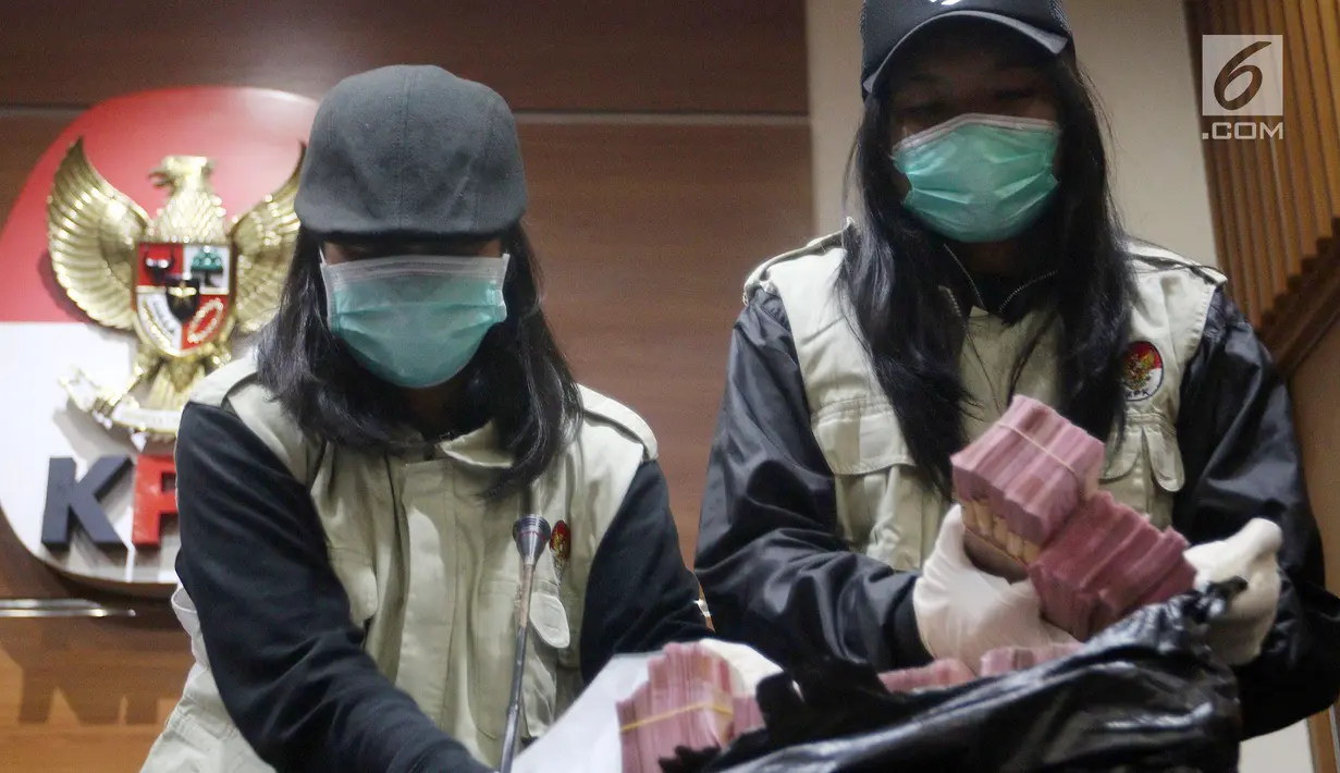 Dua penyidik KPK menunjukkan barang bukti OTT uang Rp 500 juta di Gedung KPK Jakarta, Sabtu (14/7). KPK menetapkan dua tersangka OTT anggota Komisi VII DPR RI Eni Maulani Saragih dan Johannes Budisutrisno Kotjo. (Liputan6.com/Johan Tallo)