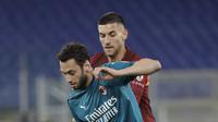 Gelandang AC Milan, Hakan Calhanoglu mengontrol bola dari kawalan gelandang AS Roma, Lorenzo Pellegrini pada pertandingan lanjutan Liga Serie A Italia di stadion Olimpiade, Italia,Senin (1/3/2021). Saat ini AC MIlan mengemas 52 poin terpaut 4 poin dari Inter Milan. (AP Photo/Gregorio Borgia)