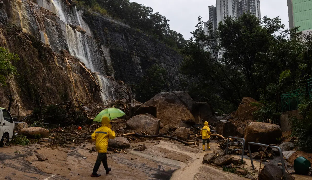 Hujan lebat mulai mengguyur Hong Kong pada Kamis (7/9) menjelang tengah malam. Para pekerja berjalan melewati tanah longsor setelah hujan badai di Hong Kong, Jumat, 8 September 2023. (AP Photo/Louise Delmotte)