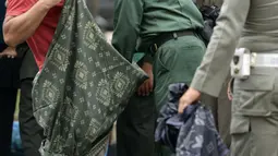 Polisi Syariat Islam memakaikan kain sarung pada warga bercelana pendek saat razia penertiban hukum syariat islam di Banda Aceh, Aceh, Selasa (19/9). Selain diberikan sarung, mereka dibina supaya berpakaian sesuai dengan peraturan (CHAIDEER MAHYUDDIN/AFP)