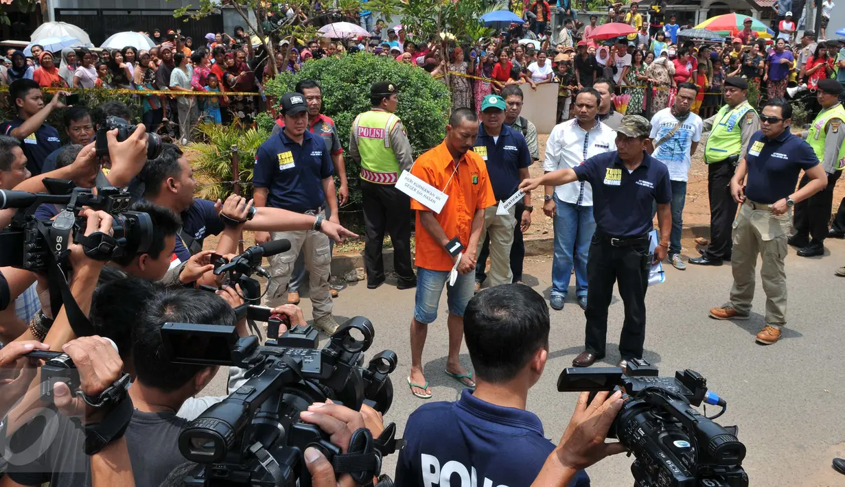 Heri alias GW, tersangka pembunuhan Dayu Pri Ambarita (45) dan anaknya Yuel Imanuel (5) memperagakan adegan saat rekonstruksi kasus pembunuhan sadis ibu dan anak di Perumahan Aneka Elok, Cakung, Jakarta, Selasa (27/10). (Liputan6.com/Andrian M Tunay)