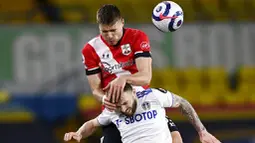 Pemain Southampton, Jan Bednarek, duel udara dengan pemain Leeds United, Stuart Dallas, pada laga Liga Inggris di Stadion Elland Road, Selasa (23/2/2021). Leeds United menang dengan skor 3-0. (Laurence Griffiths/Pool via AP)