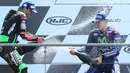 Pembalap Movistar Yamaha dan Tim Yamaha Tech 3, Maverick Vinales dan Johann Zarco saling menyemprotkan sampanye di podium MotoGP Prancis, Minggu (21/5). Vinales menjuarai MotoGP Prancis disusul Zarco yang menempati posisi kedua. (AP Photo/David Vincent)