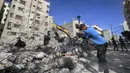 Seorang pekerja Palestina memecahkan puing-puing dari sebuah bangunan yang hancur selama konflik Mei 2021 antara Hamas dan Israel di Kota Gaza, Sabtu (5/6/2021). (MAHMUD HAMS/AFP)