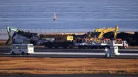 Para pekerja mulai membersihkan puing-puing dari pesawat Japan Airlines yang terbakar. Pembersihan dilakukan tiga hari usai tabrakan yang menewaskan lima awak pesawat penjaga pantai di Bandara Haneda, Tokyo, Jepang. (Kyodo News via AP)