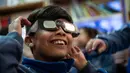Seorang anak sekolah mencoba kaca mata khusus untuk melihat gerhana matahari total di sekolah Pedro Pablo Munoz di La Higuera, Wilayah Coquimbo, di gurun Atacama, Santiago, Chile (1/7/2019). AFP Photo/Martin Bernetti)
