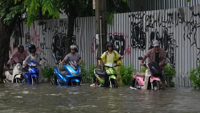 Sejumlah pria mendorong sepeda motor sambil menerobos genangan banjir akibat hujan deras di Bangkok, Thailand, Sabtu (26/9/2026).