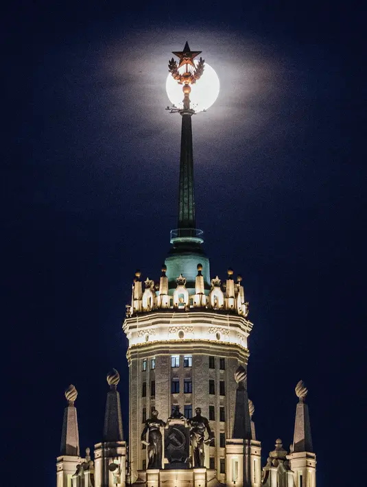 Pemandangan supermoon terlihat di belakang puncak gedung pencakar langit era Stalin di Moskow, Rusia, Selasa (7/4/2020). Fenomena dimana bulan berada pada titik terdekat dengan bumi ini merupakan penampakan supermoon terbesar di tahun 2020. (Dimitar DILKOFF/AFP)