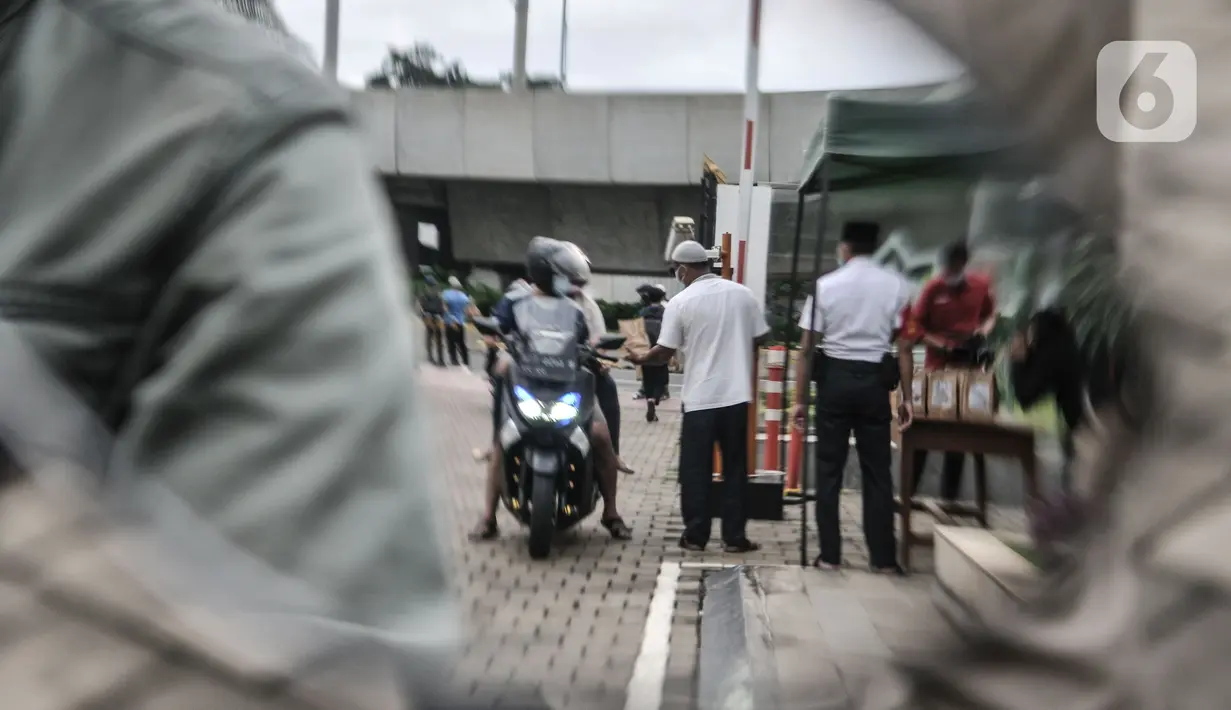 Petugas membagikan takjil kepada pengendara secara drive thru di Kompleks Masjid Al-Azhar, Jakarta, Selasa (13/4/2021). Pengelola Masjid Al-Azhar menyiapkan 500 bungkus takjil per hari yang dibagikan secara drive thru guna mencegah penyebaran COVID-19. (merdeka.com/Iqbal S. Nugroho)