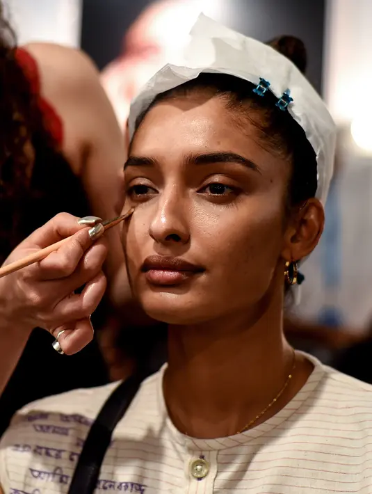 Seorang model India saat dirias oleh kru makeup di belakang panggung sebelum tampil di catwalk selama Lakmé Fashion Week (LFW) Summer Resort 2019 di Mumbai, India (31/1). (AFP Photo/Sujit Jaiswal)