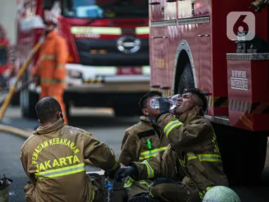Petugas pemadam kebakaran beristirahat setelah melakukan pendingan di Gedung Kejaksaan Agung RI yang terbakar, Minggu (23/8/2020). Kebakaran di gedung Kejaksaan Agung pada Sabtu (22/8) malam akhirnya padam dan kini bangunan tersebut menyisakan bagian hitam legam. (Liputan6.com/Faizal Fanani)