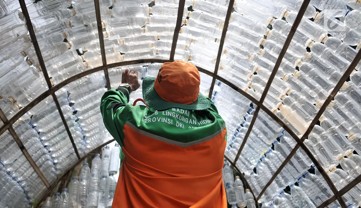 Petugas UPK Badan Air DLH DKI Jakarta saat merapikan susunan instalasi botol yang menghiasi pos di Pasar Rebo, Jakarta, Selasa (12/3). Petugas memanfaatkan botol plastik bekas untuk membangun pos cantik. (merdeka.com/Iqbal Nugroho)