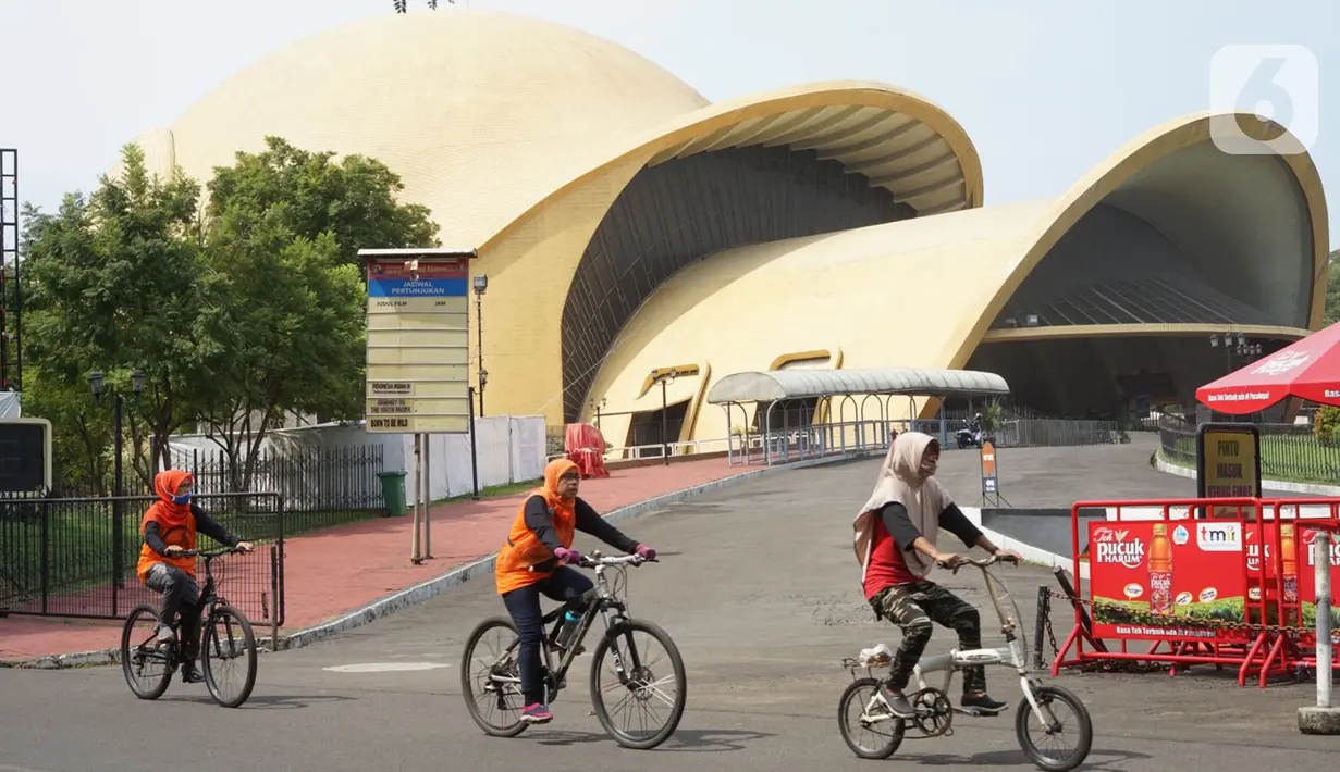 Wisatawan bersepeda mengelilingi obyek wisata Taman Mini Indonesia Indah (TMII) di Jakarta, Minggu (21/6/2020). Setelah tidak beroperasi akibat pandemi, pengelola membuka kembali TMII dengan menerapkan protokol kesehatan pencegahan COVID-19 dan pembatasan pengunjung. (Liputan6.com/Immanuel Antonius)