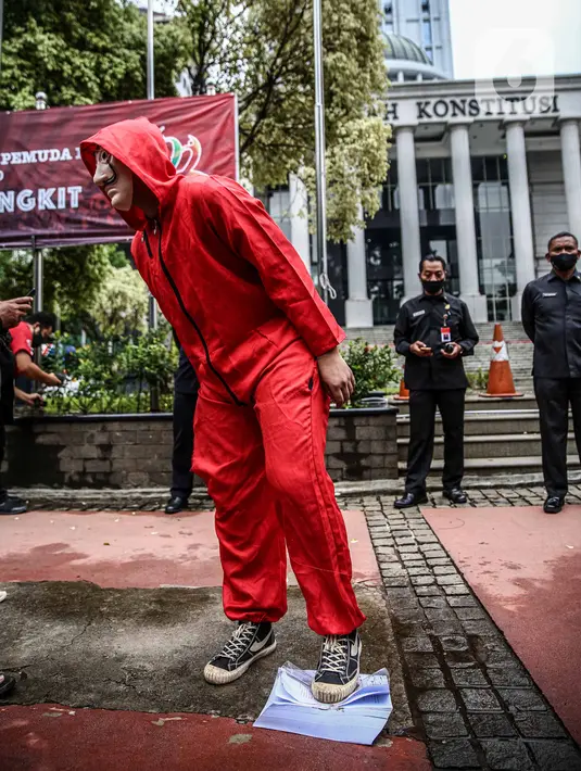 Seorang mahasiswa dari Mahasiswa Independen secara simbolis menginjak salinan naskah UU Cipta Kerja di depan Gedung MK, Jakarta, Selasa (27/10/2020). Mahasiswa menyatakan aksi tersebut bentuk ketidakpercayaan kepada MK bila proses uji materi UU Cipta Kerja dilakukan. (Liputan6.com/Faizal Fanani)