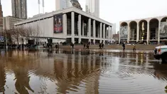Banjir menggenangi jalanan dekat Lincoln Center for the Performing Arts di New York, Amerika Serikat, Senin (13/1/2020). Banjir diakibatkan rusaknya saluran air utama yang berdiameter tiga kaki. (AP Photo/Richard Drew)