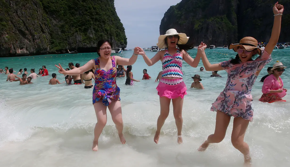 Turis melompat di atas ombak pantai Maya Bay di pulau Phi Phi Leh, Thailand, Kamis (31/5). Maya Bay akan ditutup untuk memulihkan terumbu karang yang sakit akibat peningkatan suhu serta pencemaran lingkungan oleh pengunjung. (AP Photo/Sakchai Lalit)