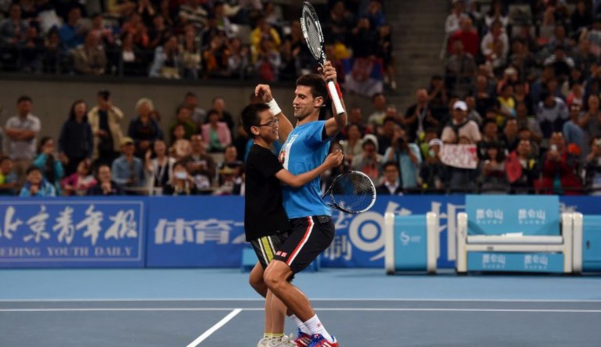 Petenis Nomor Satu Dunia Novak Djokovic menari bersama Voulentir pada acara Charity China Open tennis tournament di Beijing, Sabtu (03/10/2015).  AFP Photo / Greg Baker