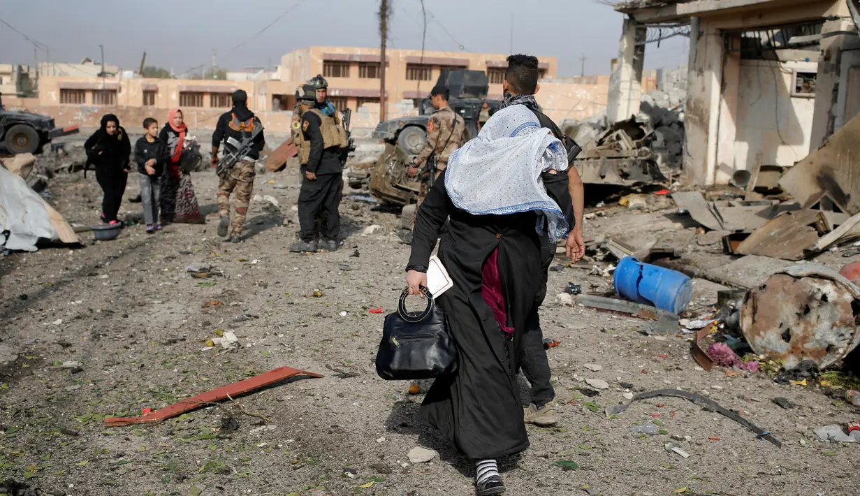 Seorang wanita menutupi wajahnya saat berusaha menyelamatkan diri menyusul serangan bom mobil bunuh diri yang dilakukan militan ISIS di kota Tahrir, Irak, 17 November 2016. (REUTERS/Goran Tomasevic)