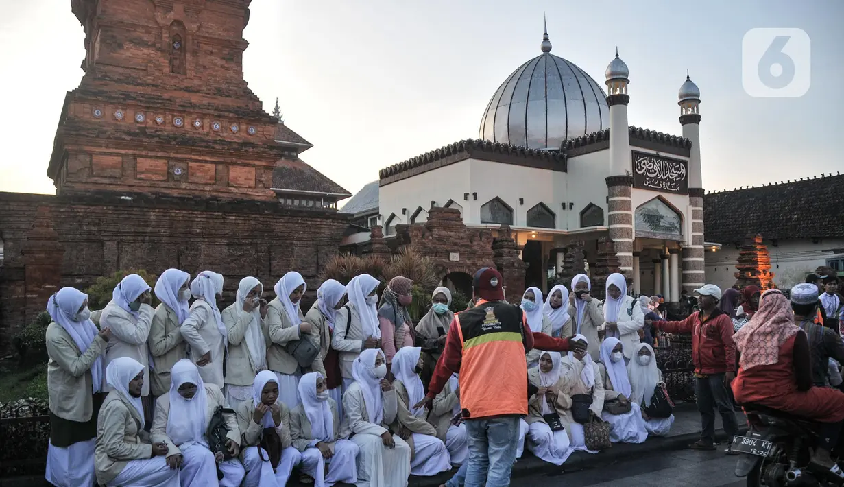 Fotografer mengarahkan gaya peziarah untuk difoto dengan latar belakang Menara Kudus, Kauman, Kabupaten Kudus, Jawa Tengah, Rabu (30/3/2022). Paguyuban Fotografer Menara Kudus sendiri telah ada sejak tahun 2000-an yang beranggotakan 30 orang. (merdeka.com/Iqbal S. Nugroho)