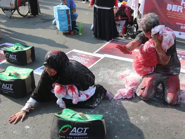 Dua relawan dari Aksi Cepat Tanggap (ACT) saat melakukan teatrikal tentang penderita rakyat Suriah yang menjadi korban peperangan di CFD Bundaran HI, Jakarta, Minggu (15/7). (Liputan6.com/Arya Manggala)