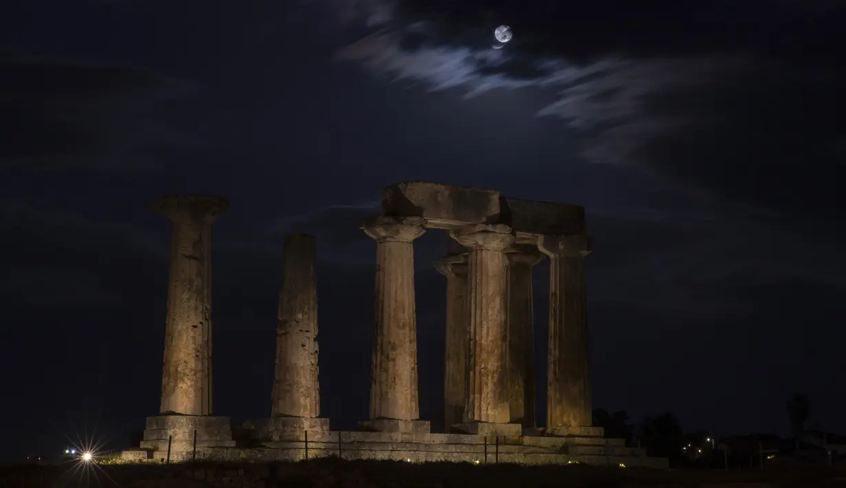 Supermoon terlihat di atas kuil Apollo, Yunani, Selasa (7/4/2020). Fenomena dimana bulan berada pada titik terdekat dengan bumi ini merupakan penampakan supermoon terbesar di tahun 2020. (AP Photo/Petros Giannakouris)