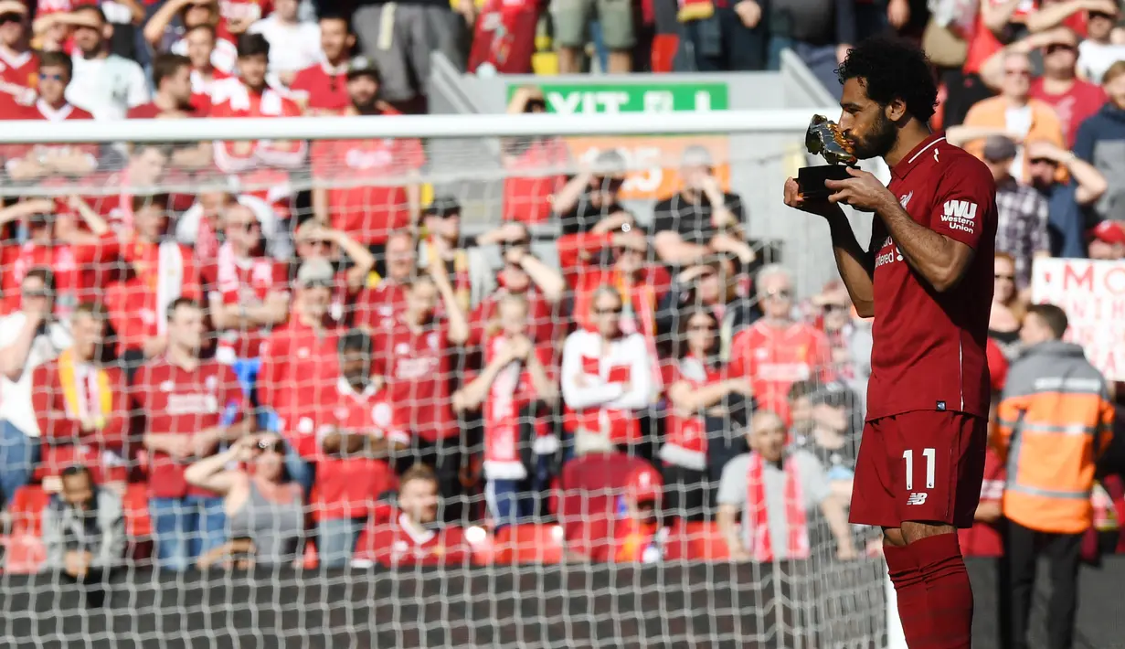 Mohamed Salah mencium penghargaan Sepatu Emas yang diraihnya setelah Liverpool menekuk Brighton and Hove Albion di Anfield, Minggu (13/5). Salah mengemas gol ke-32 musim ini saat The Reds menang telak 4-0 atas Brighton and Hove Albion. (AFP/Paul ELLIS)